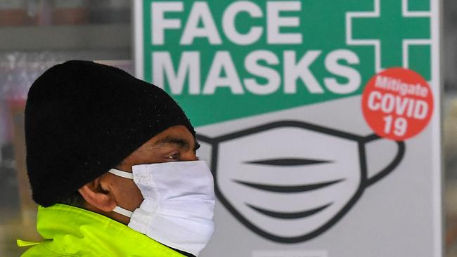 A man wearing a face mask walks past a sign advertising masks in Melbourne on Monday. Australia's second-biggest city will make it compulsory to wear a mask in public as Melbourne steps up efforts to bring a coronavirus outbreak under control. Picture: William West/AFP