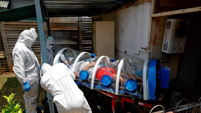 City of Tshwane's Special Infection Unit paramedics and a doctor load a man showing symptoms of COVID-19 coronavirus into the isolation chamber equipped with a negative pressure filtration system from his home in the north of Pretoria, South Africa, on January 15. Picture: AFP