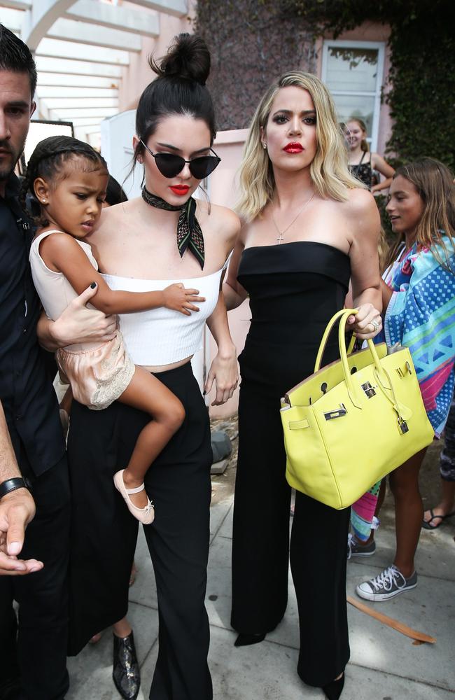 Khloe Kardashian, right, with her sister Kendall Jenner (holding North West) in San Diego, where the family celebrated their grandmother’s 82nd birthday. Picture: Splash