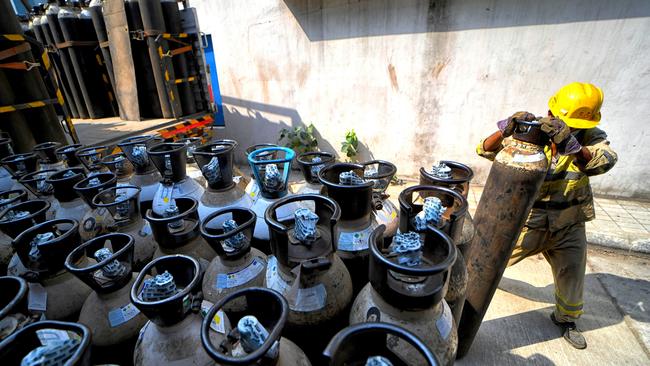 A worker loading and unloading oxygen cylinders at a government hospital in India.