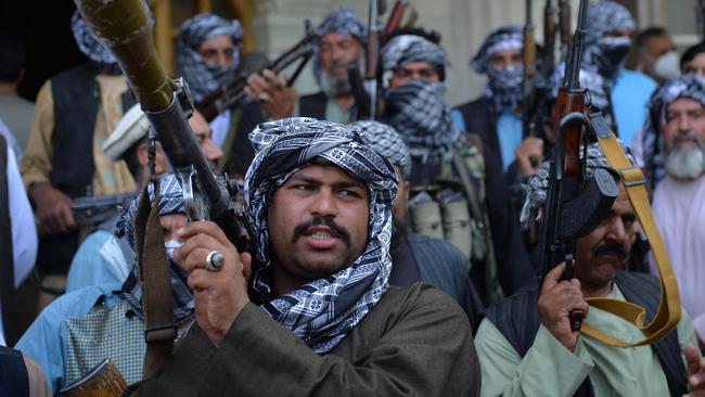 Afghan militia gather in herat to fight Taliban insurgents; and below, displaced families arrive at a nearby district of Herat. Picture: AFP