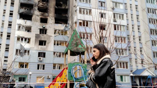 A woman talks on the phone next to a residential building following a drone attack in Kyiv region on January 24, 2025, amid the Russian invasion of Ukraine. (Photo by Tetiana DZHAFAROVA / AFP)