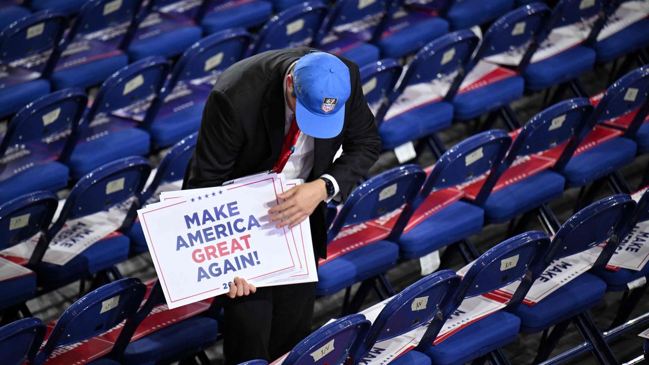 A worker sets signs reading "Make America Great Again" on attendees' seats during the last day of the 2024 Republican National Convention at the Fiserv Forum in Milwaukee. (Photo by ANGELA WEISS / AFP)