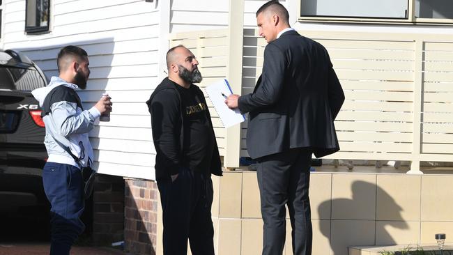 A police officer (right) is seen questioning two men outside at home at Beverly Hills, Sydney. Picture: AAP/Image Brendan Esposito