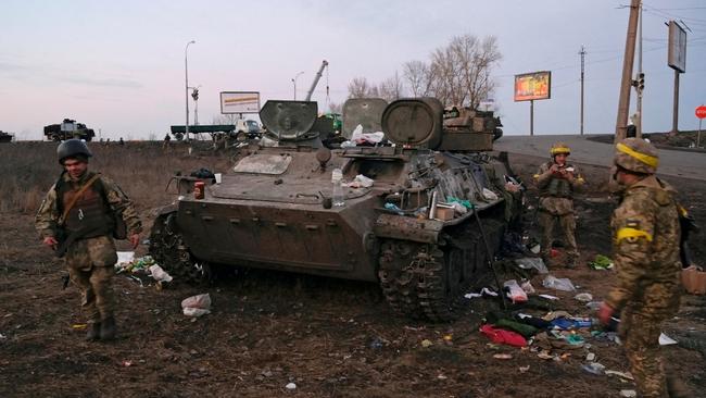 Ukrainian servicemen seen next to a destroyed armoured vehicle, which they said belongs to the Russian army, outside Kharkiv, Ukraine. Picture: Reuters