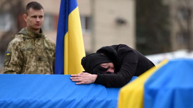 The mother of Ukrainian soldier Lubomyr Hudzeliak, who was killed during Russia's invasion of Ukraine, mourns over his flag-draped coffin during his funeral at the Lychakiv cemetery.