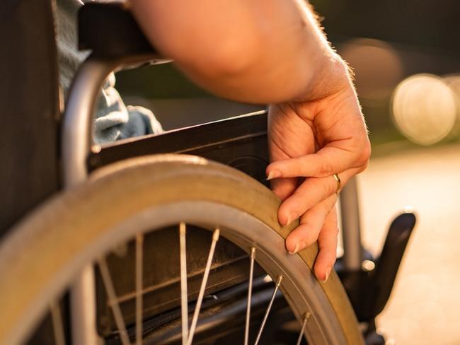 Close up women hand holding wheel on a wheelchair during sunset