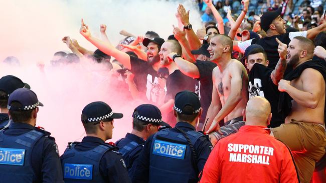 Wanderers fans in the crowd let off flares as police officers look on.