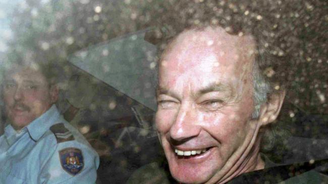 Convicted serial killer Ivan Milat smiles in a police car after attending a court in 1997.