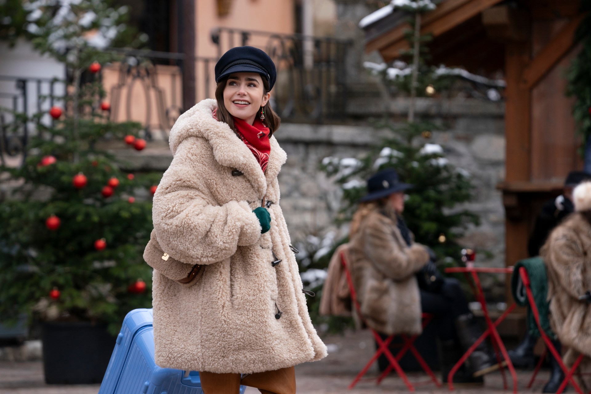 <p>Emily wears a Marant &Eacute;toile coat, Christian Louboutin boots, a Soeur bag, a Maison Michel hat and blue Rimowa bag.</p>