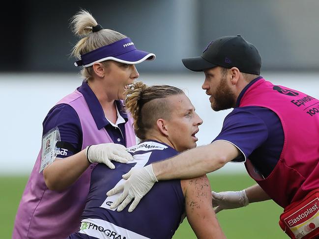 PERTH, AUSTRALIA - MARCH 28: Nat Fyfe of the Dockers is attended to by a trainer after a heavy knock from Sam J. Reid of the Giants during the 2021 AFL Round 02 match between the Fremantle Dockers and the GWS Giants at Optus Stadium on March 28, 2021 in Perth, Australia. (Photo by Will Russell/AFL Photos via Getty Images)