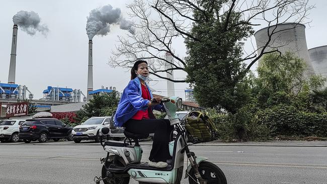 A worker with a face mask on rides past a coal fired power plant in Hanchuan, Hubei province, China. Picture: Getty