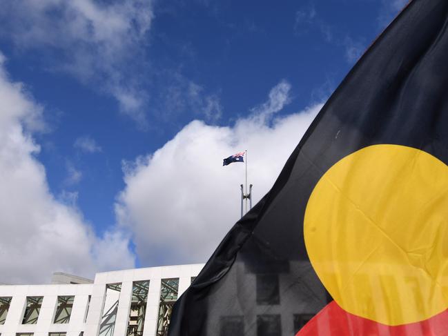 Australian Parliament House is seen through an Aboriginal flag in Canberra, Tuesday, September 5, 2017. (AAP Image/Lukas Coch) NO ARCHIVING