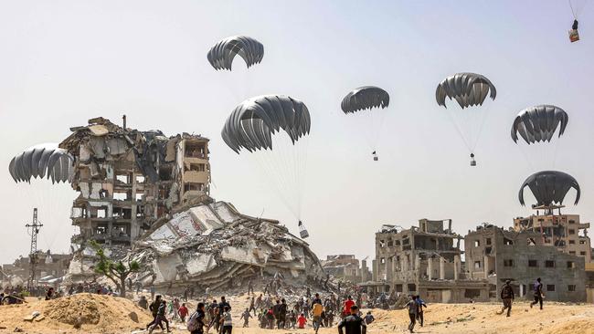 People rush to landing humanitarian aid packages dropped over the northern Gaza Strip on Tuesday. Picture: AFP