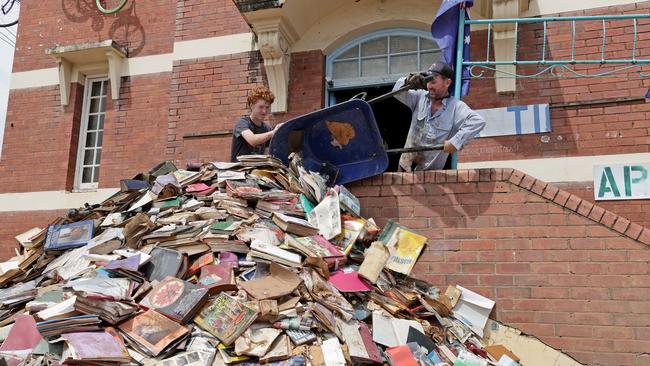 Brodey Rossington and Gary Rossington throw out damaged books from Books and Stuff in Lismore on to the footpath. Picture: Toby Zerna