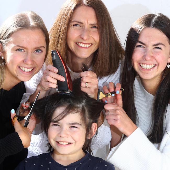 12yo Mason Boseley (bottom) preparing to get his head shaved by sister Morgan Boseley 20yrs, mum Tracey Boseley, sister Ashlee Boseley 17yrs. Picture: Glenn Ferguson