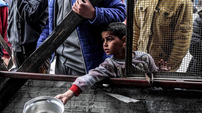 A boy holds out an empty pot as he queues for meals in Rafah. Picture: AFP