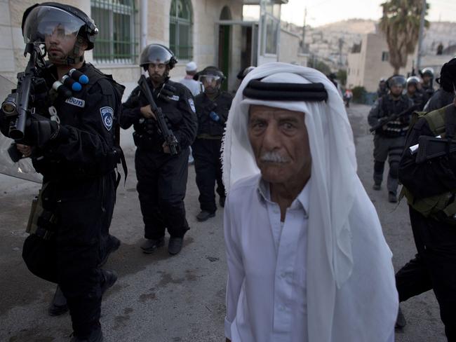 A Palestinian man walks past Israeli police officers. AFP PHOTO / AHMAD GHARABLI