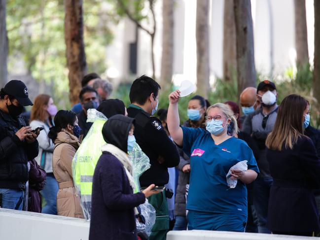 SYDNEY, AUSTRALIA - NewsWire Photos JUNE 29, 2021: NSW Health staff member is seen handing out masks at as long queues of people are seen lining up to get the Covid-19 Vaccine at the Olympic Park Vaccination Hub in Sydney Australia. Picture: NCA NewsWire / Gaye Gerard