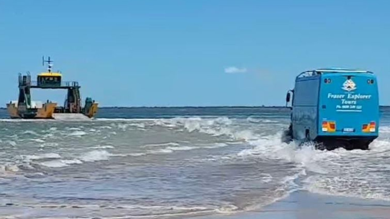 A Fraser Island tour bus drives through water to reach the barge.