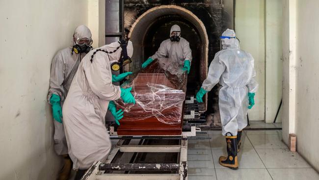 Funeral workers move a sealed coffin containing a COVID-19 victim in Surabaya, Indonesia. Picture: AFP