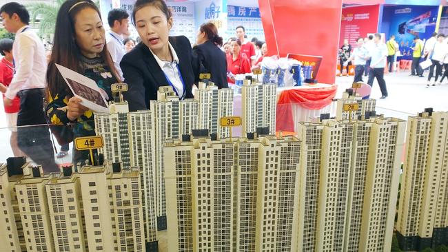 Chinese homebuyers look at housing models of a residential property project during a real estate fair in Yichang city, central China's Hubei province.