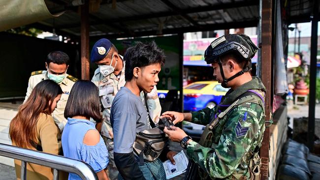 A Thai military personnel checks the bag of a Myanmar national after he cross over into Thailand, at the Tak border checkpoint.