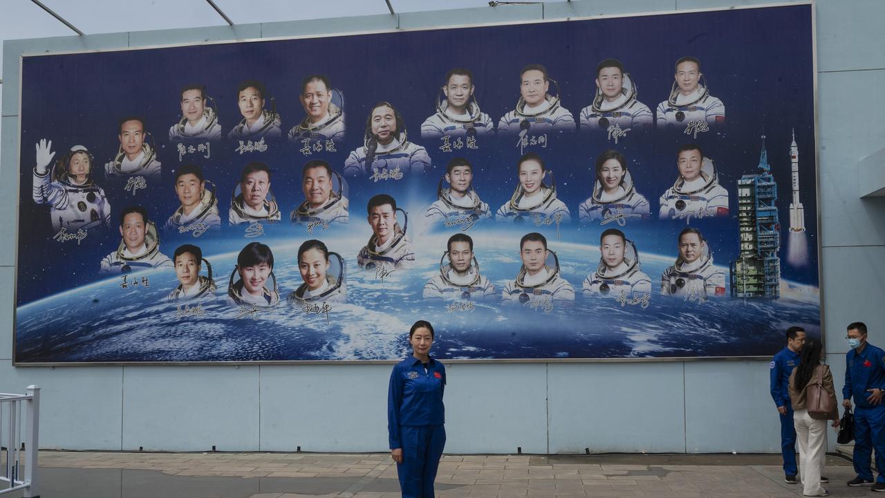 An employee of the China Manned Space Agency in front of a board showing the country’s astronauts. Picture: Getty Images