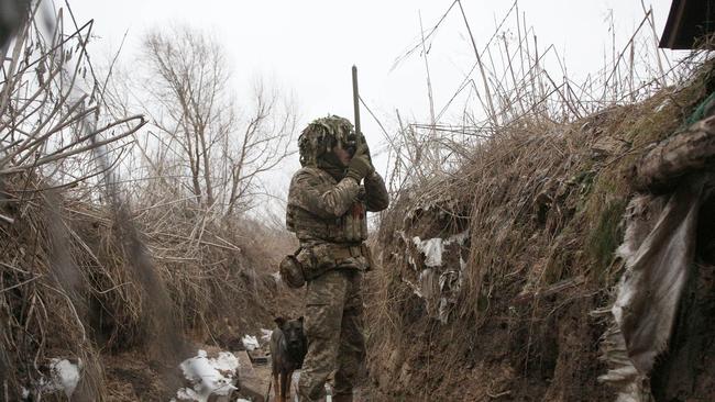 A Ukrainian reservist takes a spyglass to Russian-backed separatists from a trench at the frontline near Avdiivka, southeastern Ukraine, on Sunday. Picture: AFP