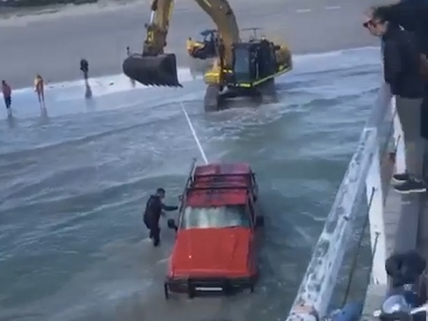 An excavator had to be brought in to remove a car from Semaphore beach after it was brought out in high tide. Picture: Timothy Kamenjarin