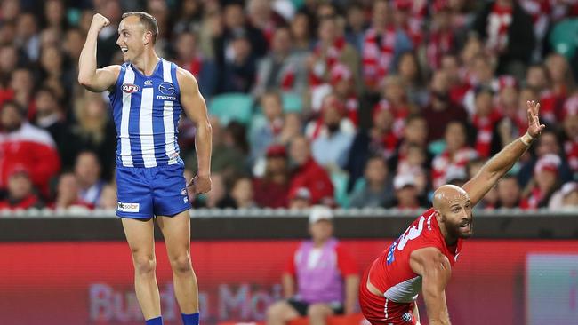 Billy Hartung of the Kangaroos celebrates kicking a goal as Jarrad McVeigh of the Swans appeals for a touch during a match in 2018. Photo by Mark Metcalfe/Getty Images