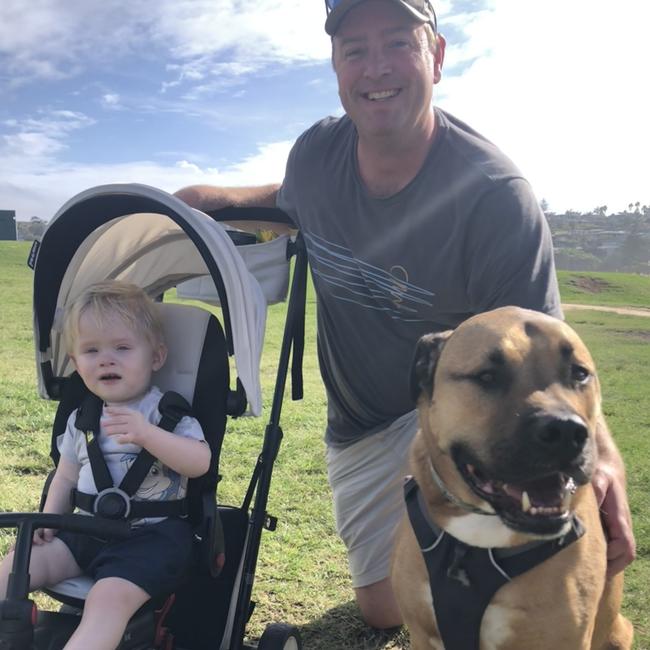 Dog owner Damien Macaulay, of Brookvale, with his son Arch, 13 months, and dog Chief, at the North Curl Curl off-leash dog park on Tuesday. Picture: Jim O’Rourke.