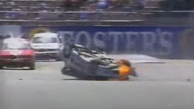 His car which is on fire skids back into the middle of the track.