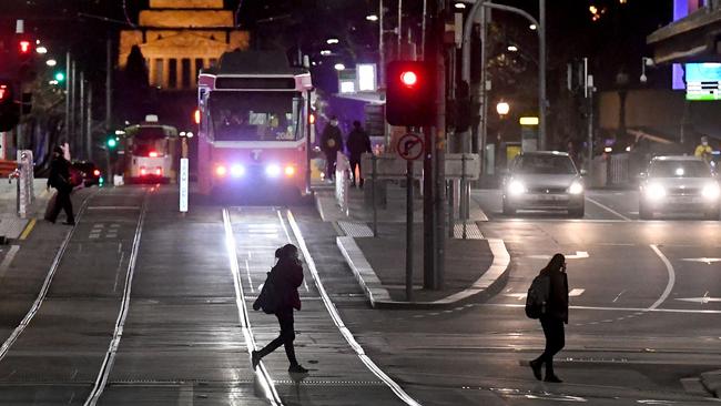 Commuters cross a street during curfew hours in Melbourne on Tuesday, as the city imposed 9pm to 5am stay-at-home restrictions against an outbreak of the Delta variant of coronavirus. Picture: AFP