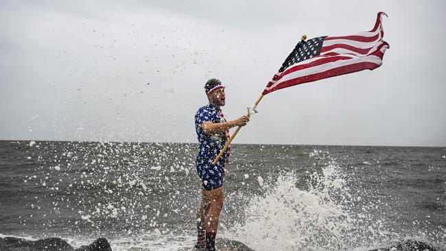 YouTuber Mark Peyton holds a US flag as he poses for his brother Matt Peyton on the shoreline ahead of the arrival of Hurricane Helene in Alligator Point, Florida. Picture: AFP