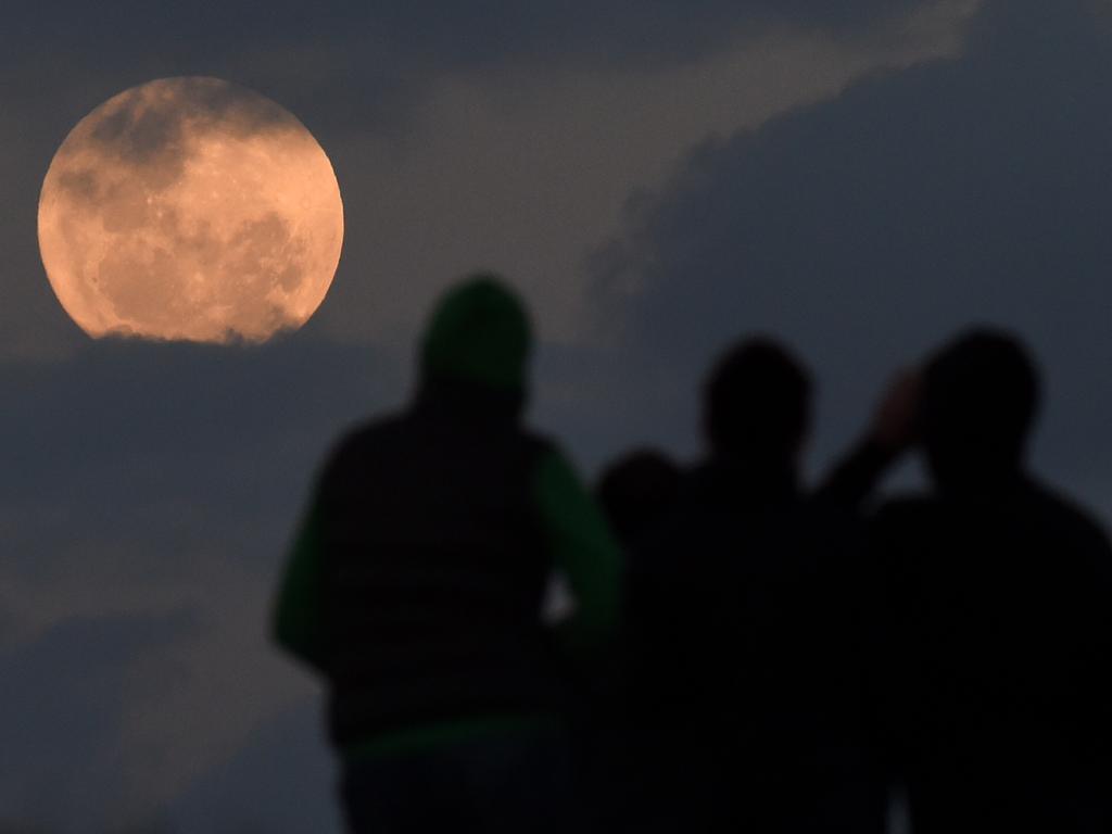 A crowd watches as the full moon is seen between the clouds from Balg Hill south of Sydney, Monday, Nov. 14, 2016. The Supermoon, at perigee is the closest it has been to Earth since January 1948. (AAP Image/Dean Lewins) NO ARCHIVING