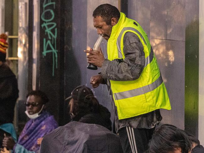 A man on Elizabeth St openly uses a bong.