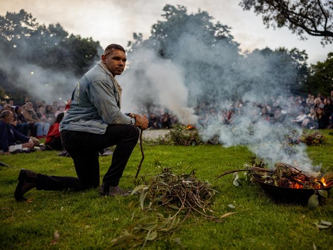 An Aboriginal man kneels in front of the fire with the crowd in the background for the Invasion Day Dawn Service Picture: Getty