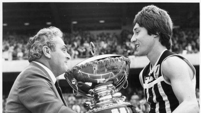 Port Adelaide  captain Brian Cunningham receives the Thomas Seymour Hill Cup trophy from SANFL president Max Basheer. after the Magpies beat South Adeklaide to win the 1979 premiership.