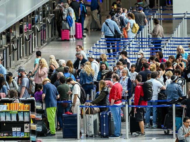 Passengers queue at the check-in counter at Duesseldorf International Airport (DUS), western Germany on July 1, 2022. - Airlines and airports are currently struggling with the lack of staff and high levels of sick leave due to the corona pandemic. As a result, flights are sometimes canceled, passengers have to wait in long queues at the airports. There is currently a shortage of around 7,200 skilled workers in the industry. To alleviate the staff shortage at German airports and the flight chaos, the German government has proposed to hire temporary staff from abroad to fill in at airports at short notice and help out with baggage handling and security checks, according to the German ministers of transport, labor and the interior at a joint press conference on June 29, 2022. (Photo by Ina FASSBENDER / AFP)