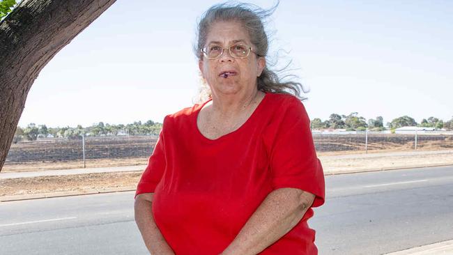 ADELAIDE, SOUTH AUSTRALIA - Advertiser Photos DECEMBER 25, 2024: Cricket Fox 61yrs in her front yard with the backdrop of the Smithfield grass fire that burnt in a direction towards Boddington Street, Donnington Street and Konanda Road. Picture: Emma Brasier