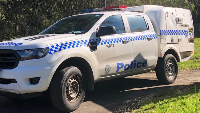 A police vehicle leaving a property in Hilversum Cres at Belrose where police arrested a man after emergency services received calls about a fire in a garage that may have contained ammunition. Picture: Jim O'Rourke