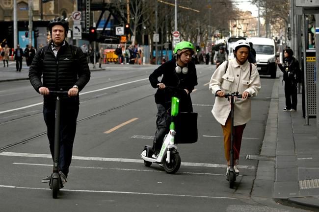 People ride e-scooters in Melbourne's central business district on August 14