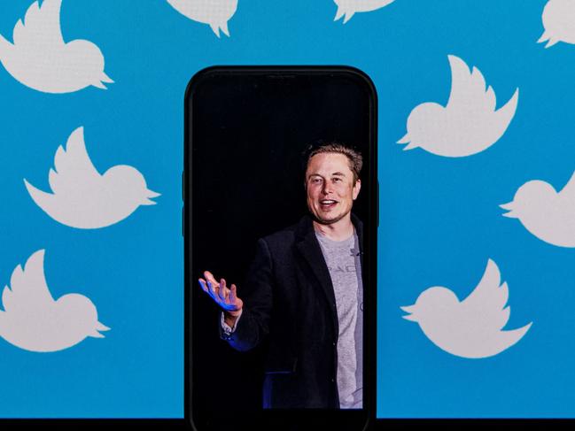 (FILES) This file photo illustration taken on August 5, 2022, shows a cellphone displaying a photo of Elon Musk placed on a computer monitor filled with Twitter logos in Washington, DC. - Twitter announced Sunday it would no longer allow users to promote their accounts on several rival social media platforms including Facebook and Instagram, but the site's mercurial owner Elon Musk appeared to backtrack on the new policy just hours later. (Photo by SAMUEL CORUM / AFP)