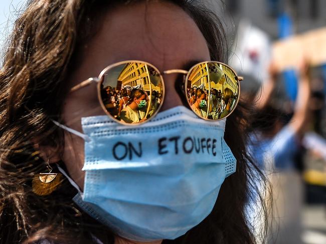 A woman wears a protective face mask with the words, 'We are suffocating' during a protest in support of the healthcare sector in Brussels. Picture: AFP