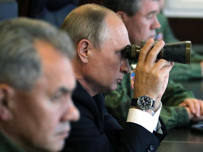 TOPSHOT - Russian President Vladimir Putin (C), accompanied by Defence Minister Sergei Shoigu (L), uses a pair of binoculars as he inspects the joint Zapad-2017 (West-2017) Russian military exercises with Belarus at the Luzhsky training ground in the Leningrad region on September 18, 2017. / AFP PHOTO / SPUTNIK / Mikhail KLIMENTYEV