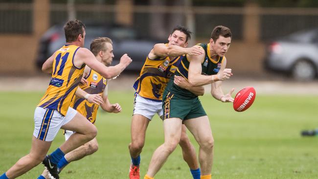 Pembroke's Alexander Jarvis gets a handball off before being tackled by PHOS Camden's Harrison Cumming at Haslam Oval. Picture: MATT LOXTON