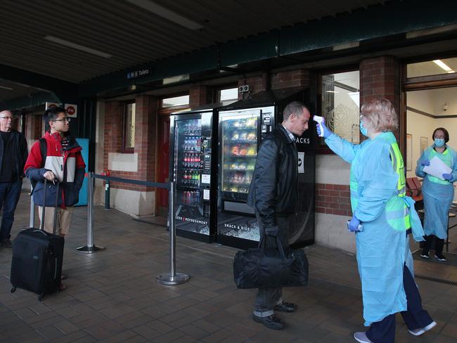 A nurse takes the temperature of an arriving rail passenger from Melbourne at Central Station on July 3 in Sydney. Picture: Getty