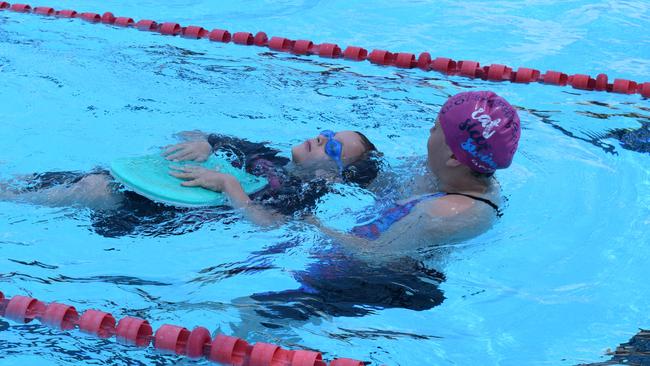 Courtney Spry helps a young swimming in their race.