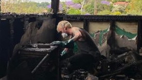 Lismore local Eli Roth digs among the ashes searching for something to salvage from the rental in Lismore after it burnt down on Monday. Picture: Supplied